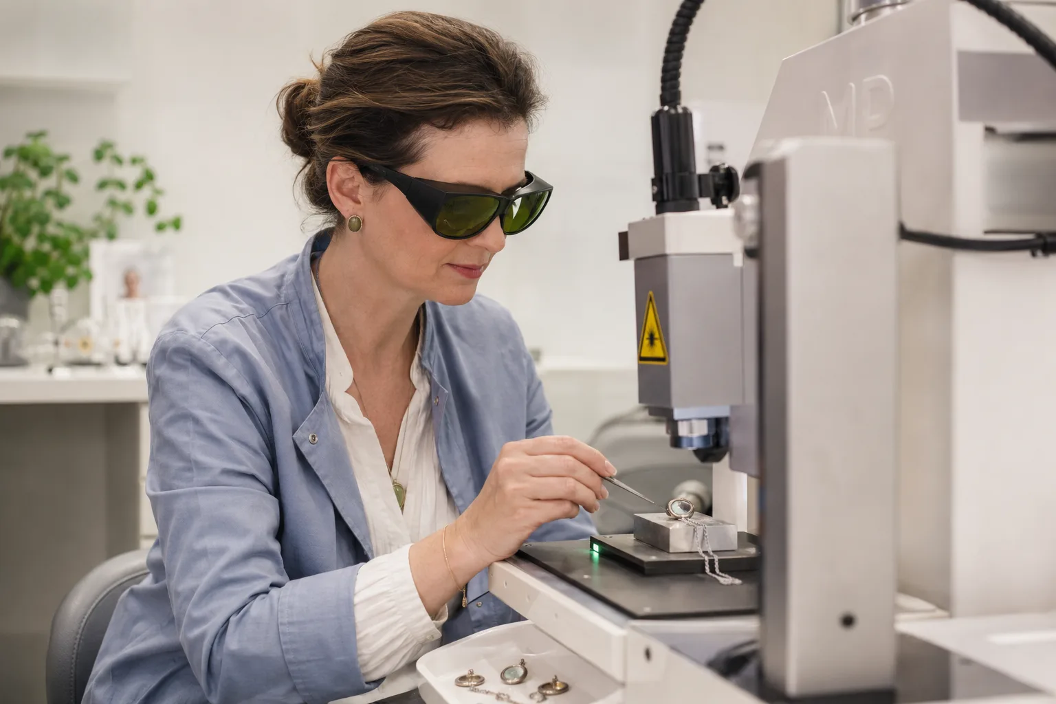 Dr. Helene Vasall at a laser engraving machine, watching an engraving in progress.